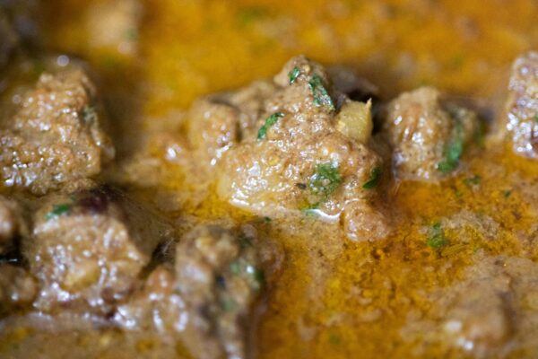 Close-up of a rich beef curry with herbs and spices, showcasing its texture and colors.