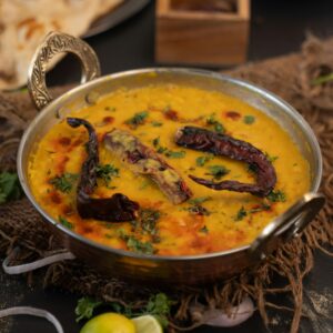 Delicious Indian lentil curry garnished with dried chilies and cilantro in an ornate bowl.