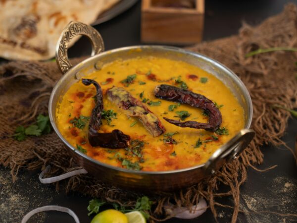 Delicious Indian lentil curry garnished with dried chilies and cilantro in an ornate bowl.