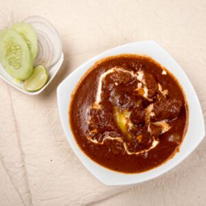 Top view of Indian kidney bean curry with cucumber, onions, and lime on the side.