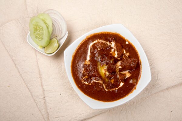 Top view of Indian kidney bean curry with cucumber, onions, and lime on the side.