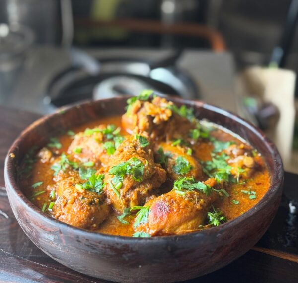 Savor the rich flavors of homemade Indian chicken curry garnished with cilantro. Perfect for food lovers.