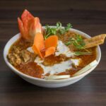 Close-up of a spicy Indian curry with fresh vegetables garnishing, showcasing vibrant culinary art.