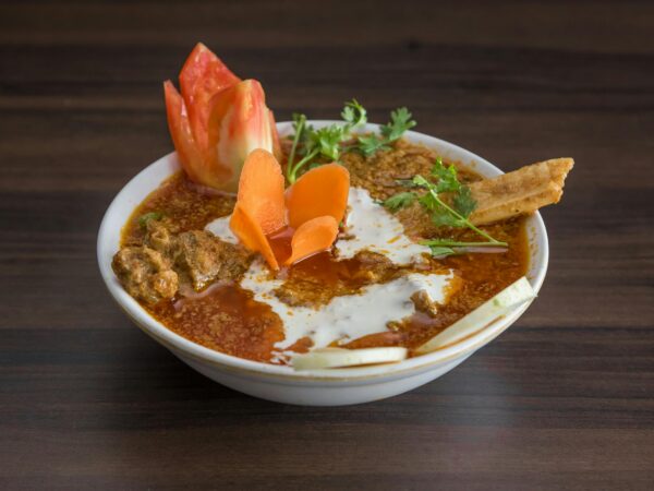 Close-up of a spicy Indian curry with fresh vegetables garnishing, showcasing vibrant culinary art.
