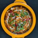 Top view of a flavorful Indian curry garnished with herbs and chilies, served in a vibrant dish.