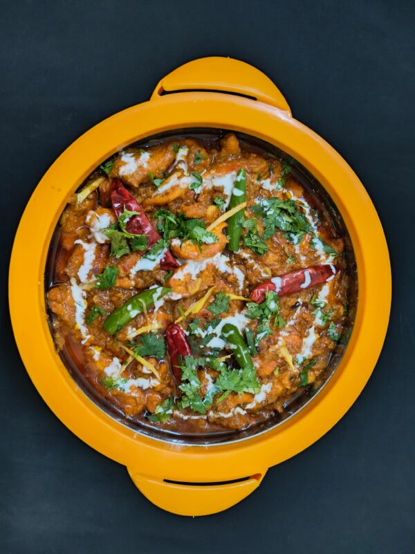 Top view of a flavorful Indian curry garnished with herbs and chilies, served in a vibrant dish.
